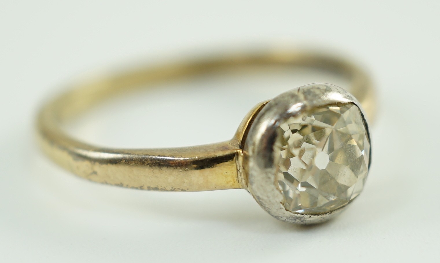 An antique yellow metal and collet set solitaire old cushion cut diamond ring